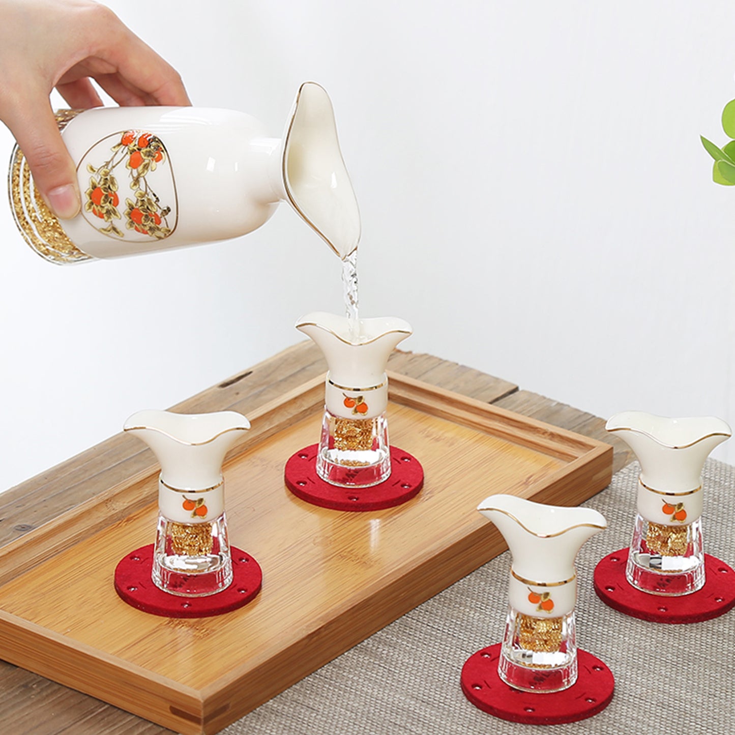 一隻手拿著如意金箔陶瓷酒具的酒壺倒酒進酒杯的樣子,清楚呈現酒壺、酒杯的使用方式以及比例尺